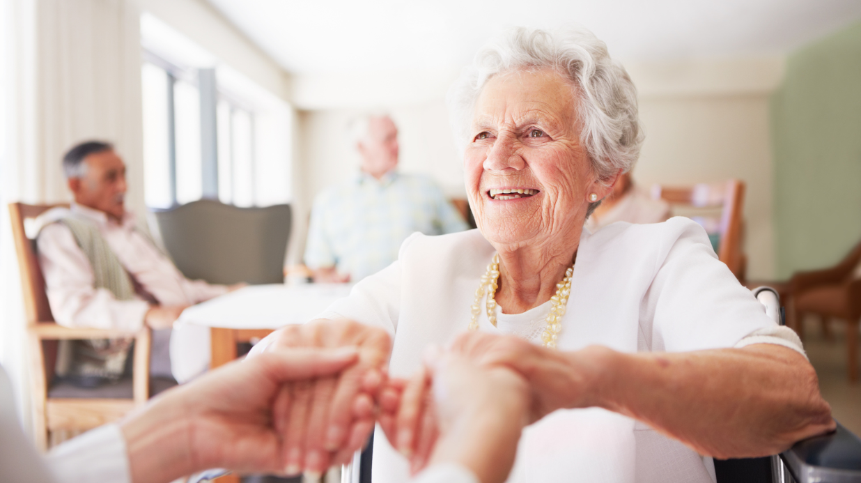 Blog Covers – 2025-09-17T144134.198 Senior woman in a nursing home, holding the hands of a nurse