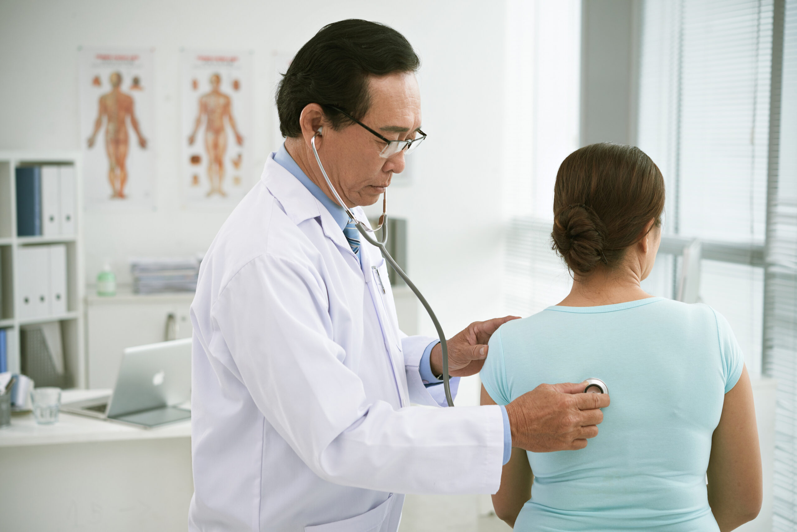 Mature experienced doctor checking breath of female patient