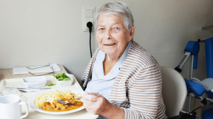 Senior woman eating rice and curry at a table