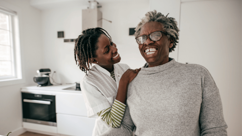 Senior woman and her adult daughter laughing in the kitchen