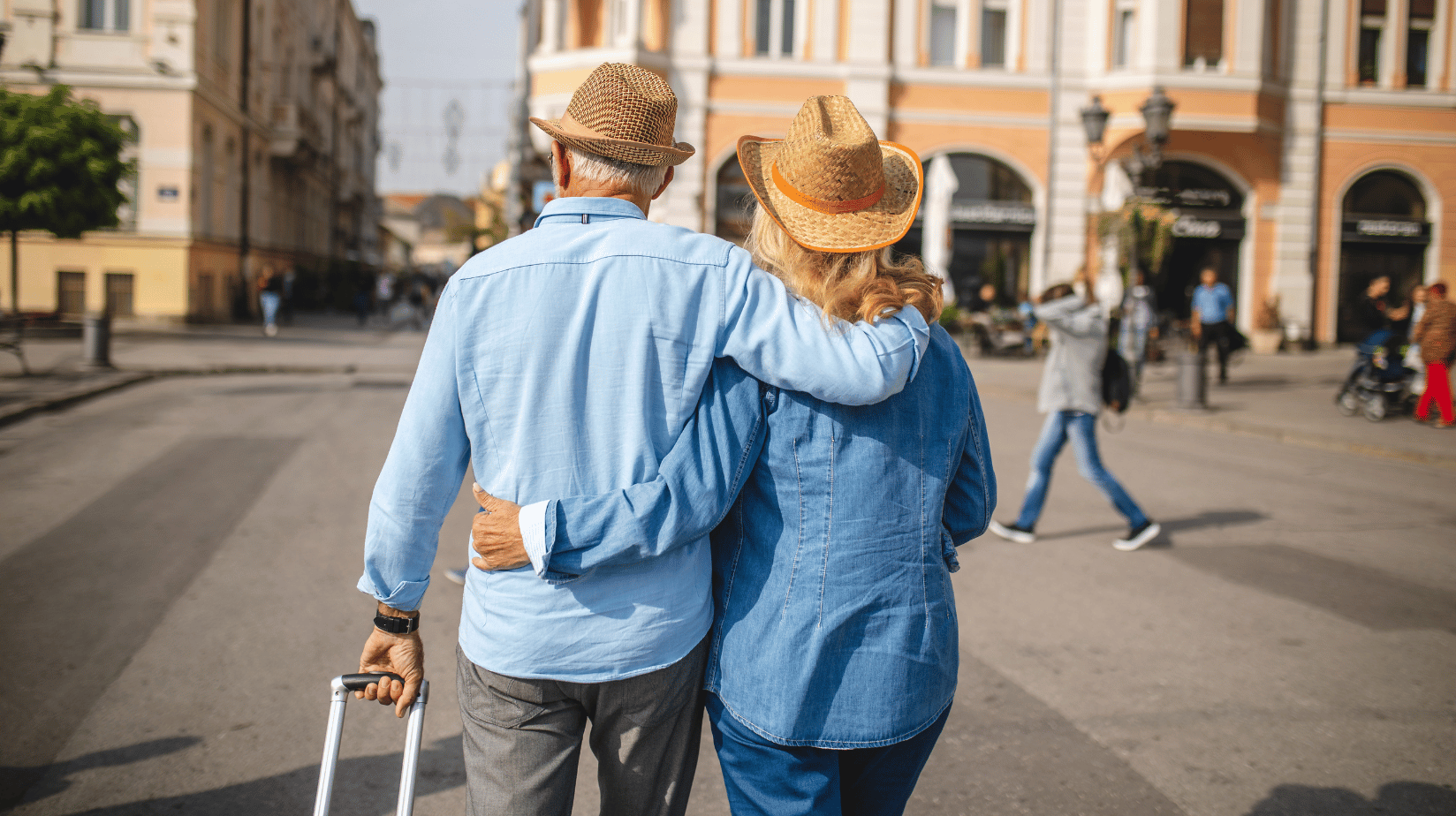Senior couple on vacation, rolling a suitcase behind them