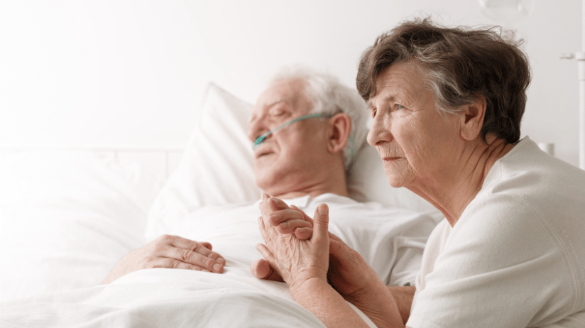Senior woman sitting with her husband who is in the hospital