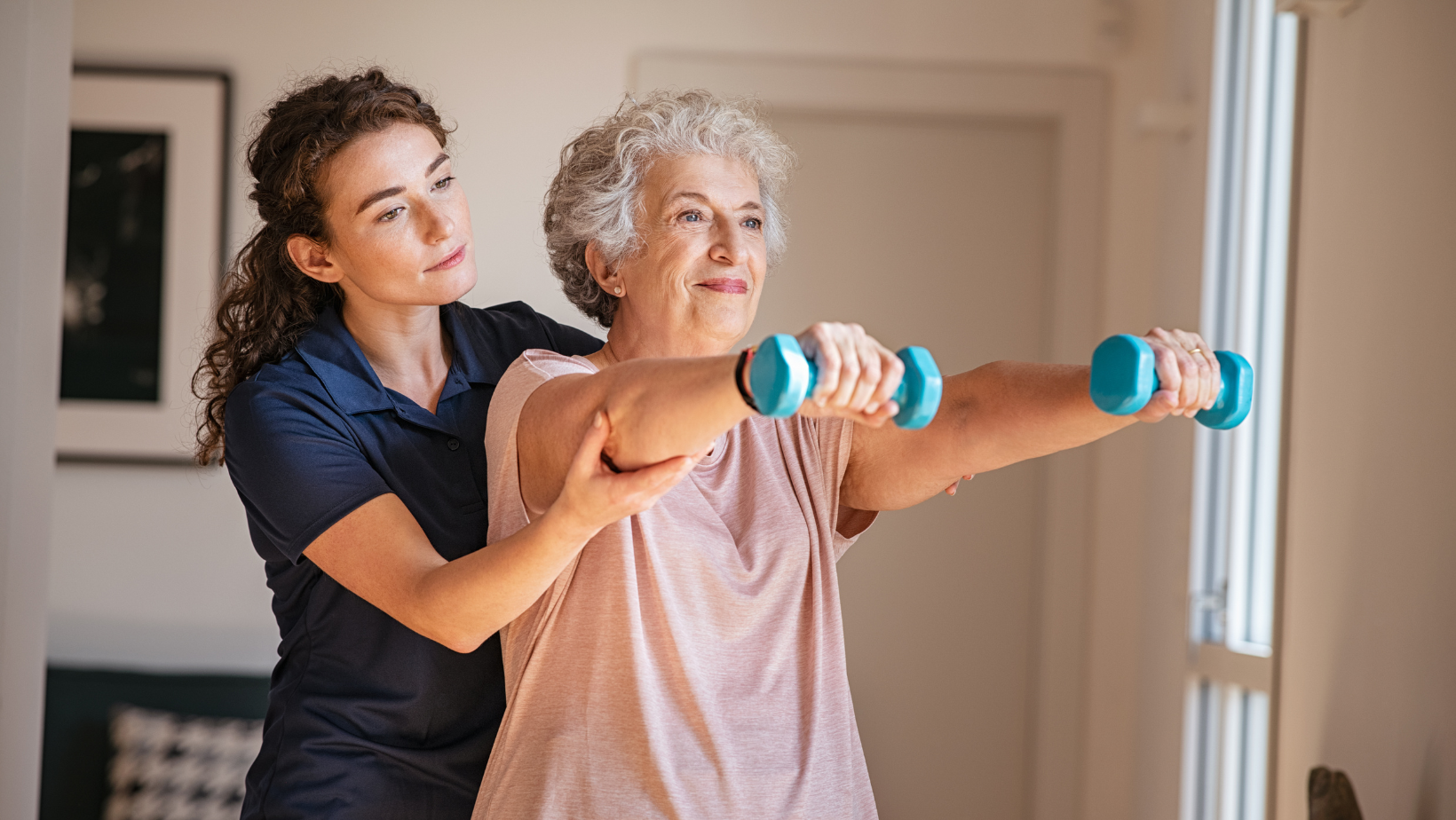 Caregiver helping a senior woman with arm exercises