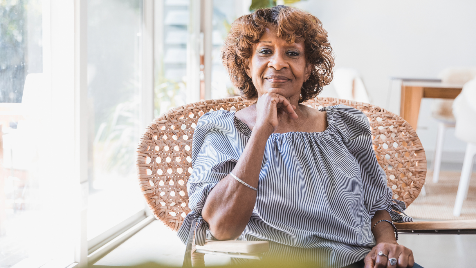Senior woman sitting in a wicker chair and smiling confidently