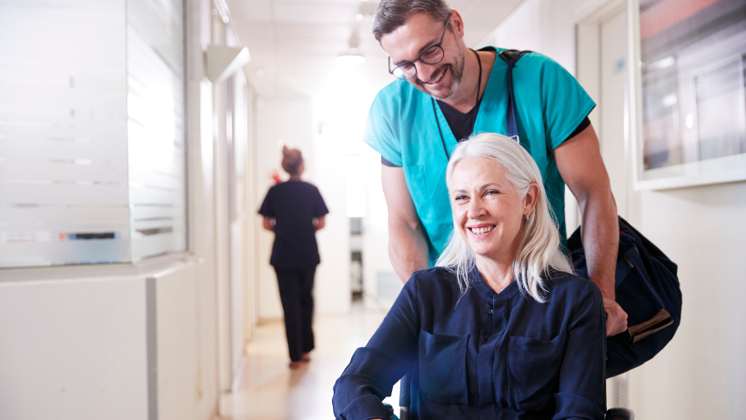Nurse pushing a senior woman in a wheelchair through a hospital
