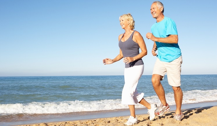 Senior couple runing along the beach