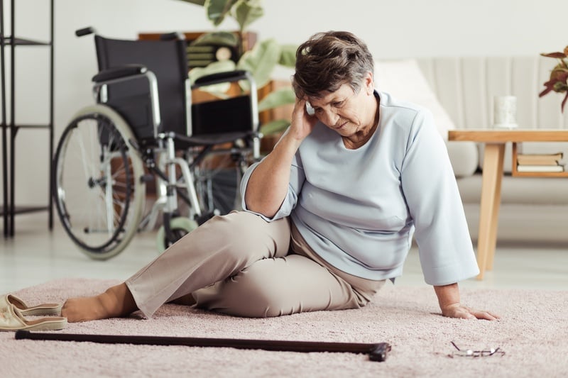 Senior woman sitting on the floor after a fall from a wheelchair