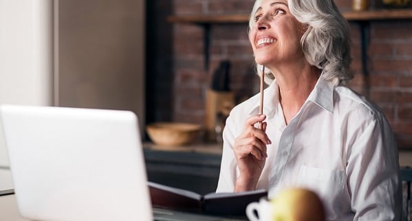 Senior woman smiling confidently behind a computer