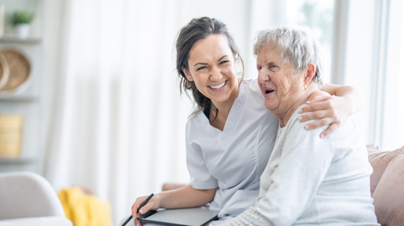 Female caregiver smiling with a senior woman