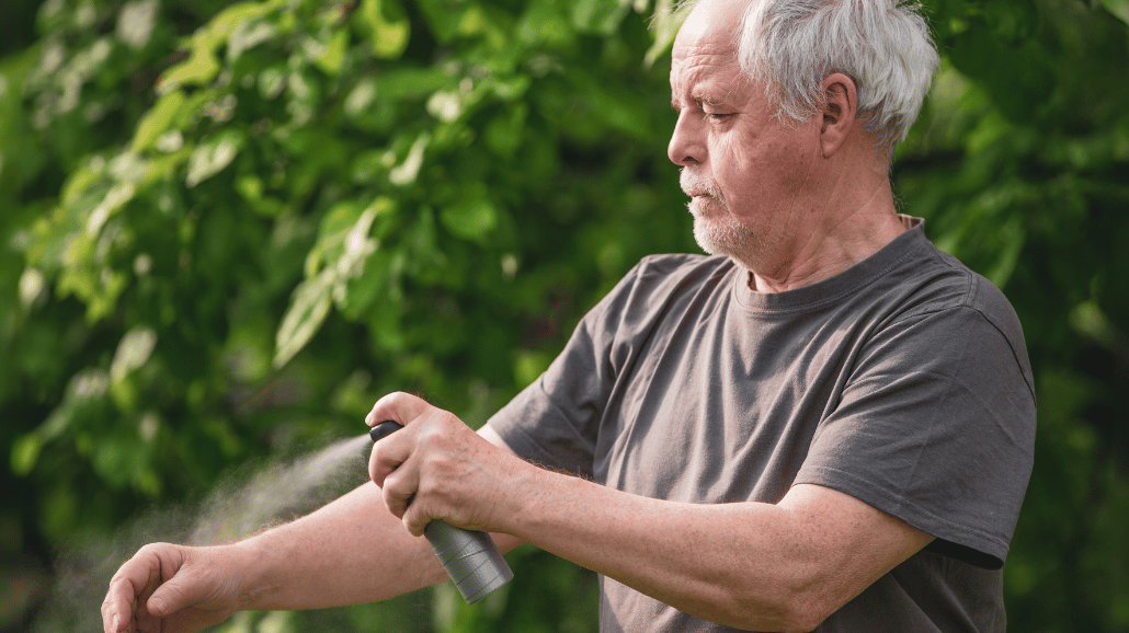 Senior man putting on spray sunscreen