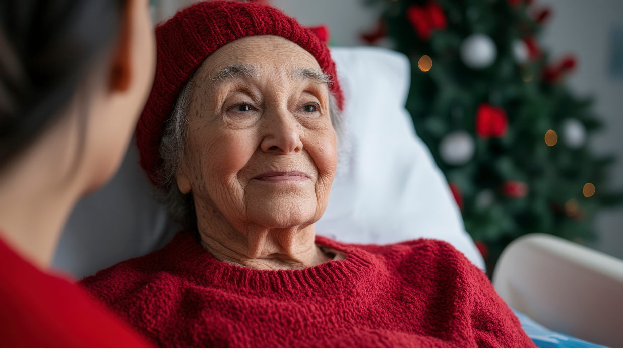Senior lying in hospital bed at home in front of a Christmas tree